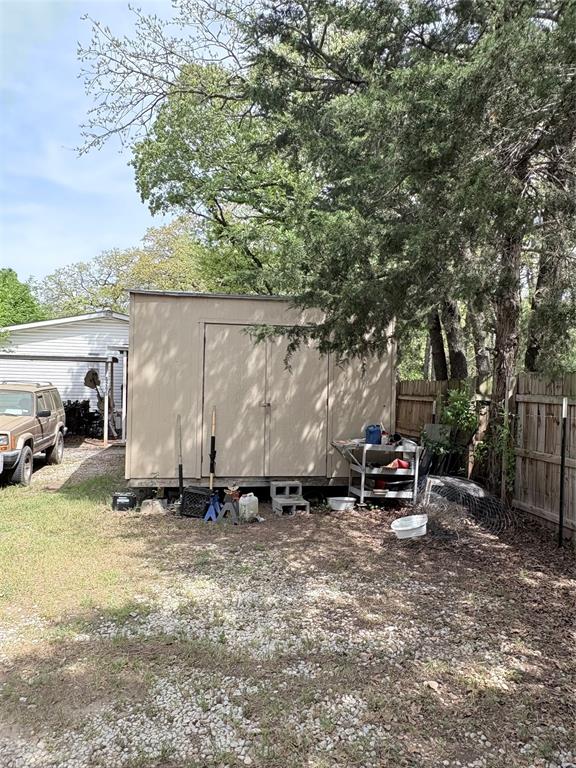 6295 Rendon New Hope Road Fort Worth, TX 76140 - Photo 29 of 38 Freestanding storage shed with double doors, wood-paneled fencing, and mature trees providing natural shade
