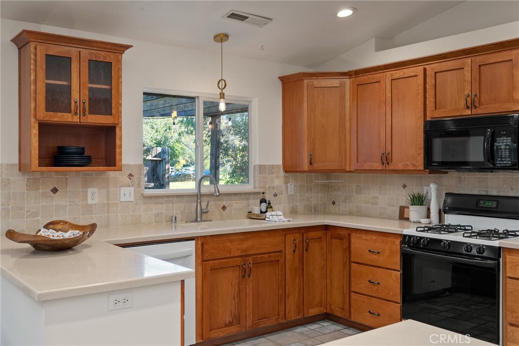 3 Cardiff Court Chico, CA 95973 - Photo 14 of 25 a kitchen with stainless steel appliances granite countertop a sink dishwasher stove and microwave with wooden cabinets