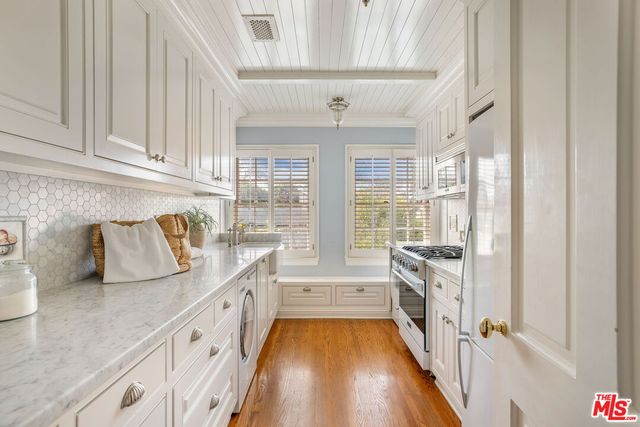 a hallway with white cabinets and wooden floor