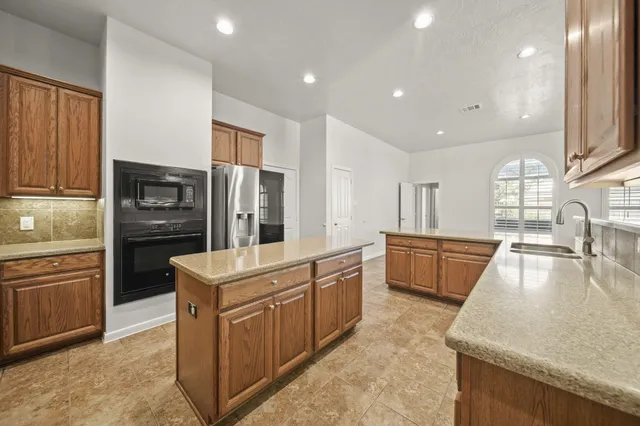a kitchen with stainless steel appliances granite countertop a refrigerator a stove and a sink