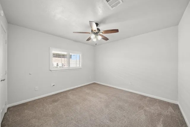 an empty room with windows and chandelier fan