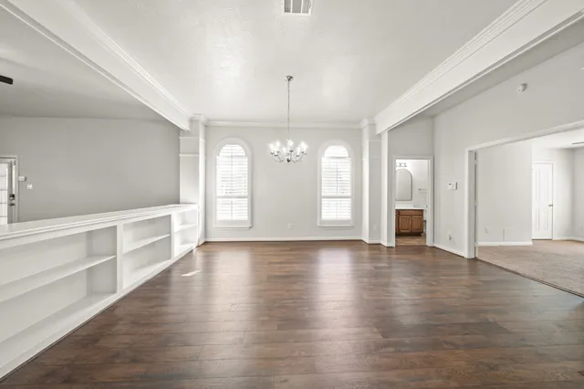 a view of an empty room with window and wooden floor