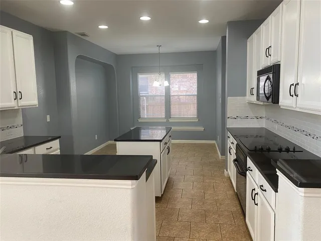 a kitchen with stainless steel appliances granite countertop a stove a sink and a microwave