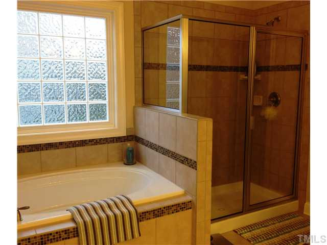 3614 Silver Forrest Lane Raleigh, NC 27614 - Photo 18 of 25 Another view of the spacious master bath featuring a soaking tub and oversized shower. Tile surrounds the shower, tub, and floor. The block glass window lets in great natural light while still providing privacy. Master Bath/Spa