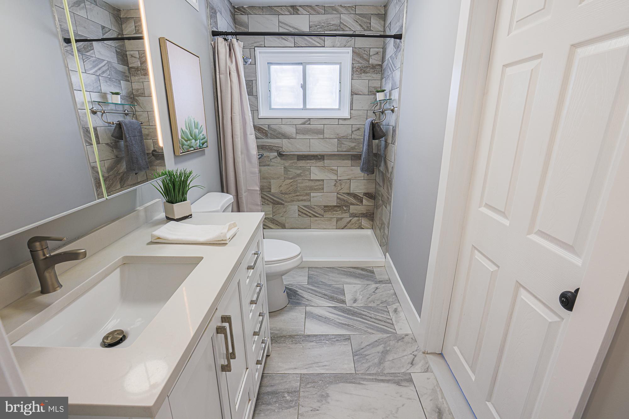 3715 Washington Avenue Baltimore, MD 21244 - Photo 40 of 57 a bathroom with a sink a mirror and a shower