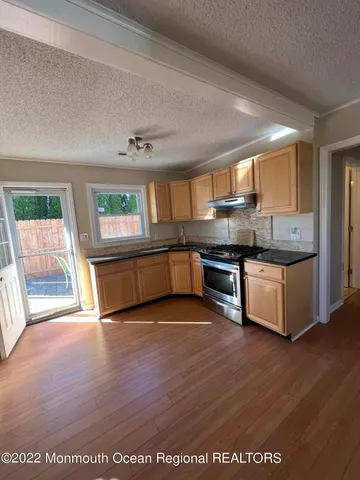 a large kitchen with granite countertop a stove and a wooden floors