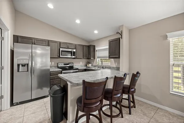 a kitchen with stainless steel appliances granite countertop a refrigerator a stove a sink a dining table and chairs