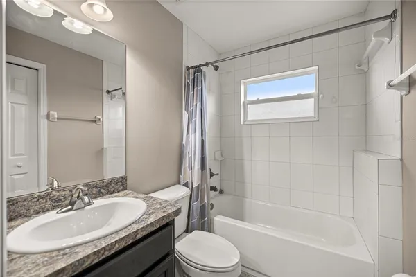 a bathroom with a granite countertop sink toilet mirror and shower