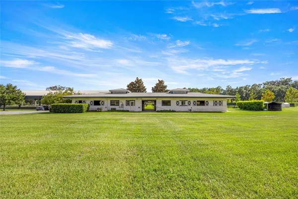 a view of a big house with a big yard and large trees