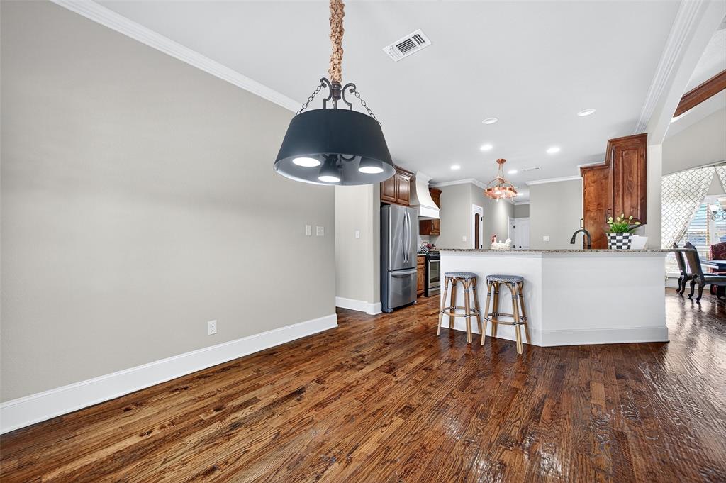 2420 Remuda Drive Sherman, TX 75092 - Photo 11 of 40 a kitchen with stainless steel appliances a dining table chairs a stove and a refrigerator with wooden floor