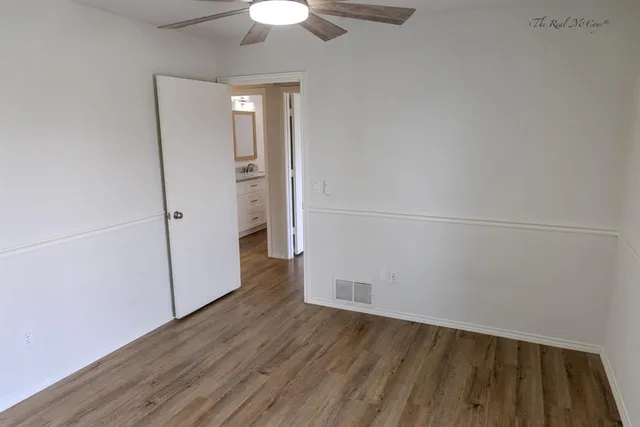 an empty room with wooden floor and a ceiling fan