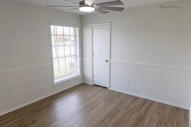 an empty room with wooden floor fan and windows