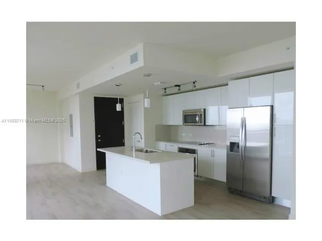 a kitchen with kitchen island a sink a refrigerator and a stove