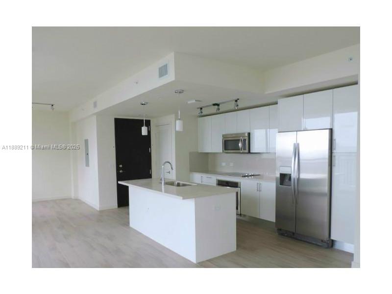 a kitchen with kitchen island a sink a refrigerator and a stove