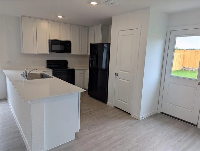 a kitchen with a sink a microwave a refrigerator and cabinets