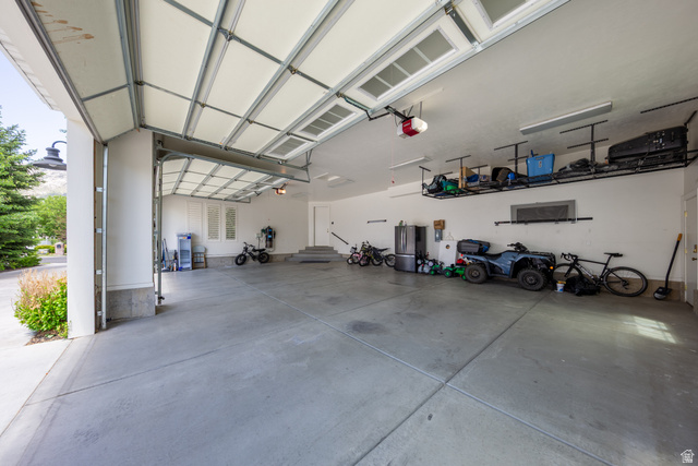 630 East Center Street Alpine, UT 84004 - Photo 78 of 115 Spacious garage featuring concrete flooring, an automatic overhead door, and two wall-mounted storage racks