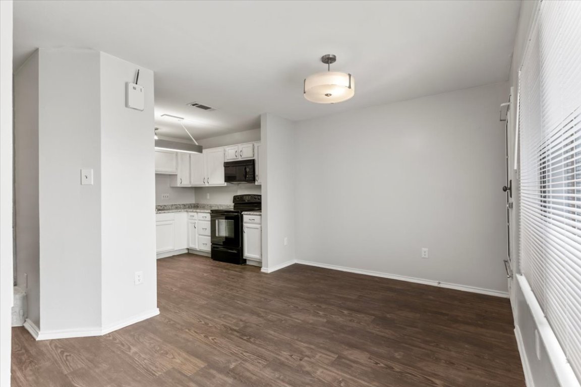 1740 Timber Ridge Road, Unit 132 Austin, TX 78741 - Photo 11 of 29 an empty room with wooden floor kitchen view and windows