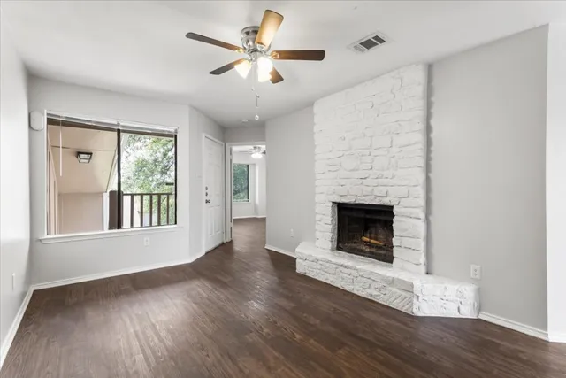 a view of an empty room with wooden floor fireplace and a window