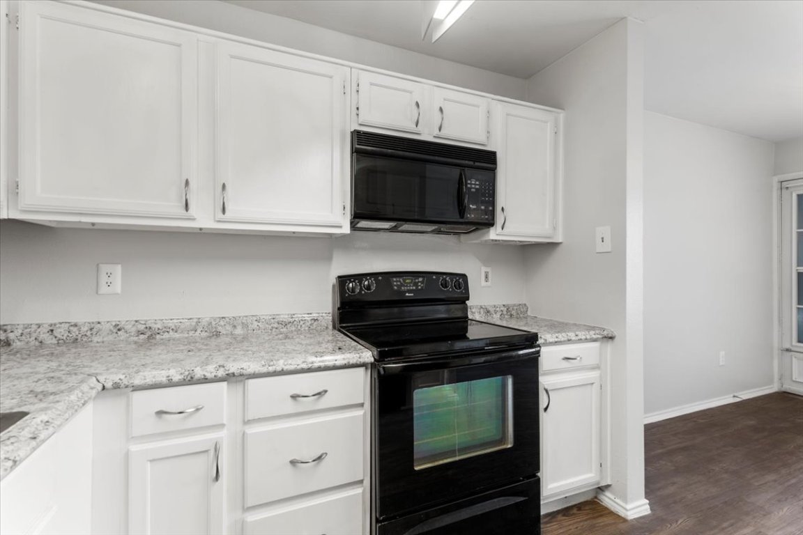 1740 Timber Ridge Road, Unit 132 Austin, TX 78741 - Photo 7 of 29 a kitchen with granite countertop white cabinets and black appliances