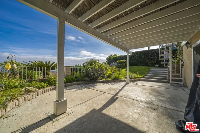 a view of backyard with large window and potted plants