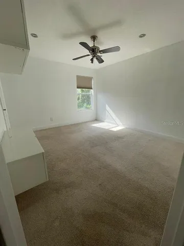 an empty room with windows and fan