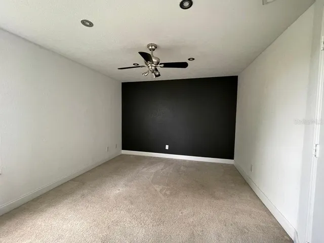 a view of a room with a ceiling fan and carpet