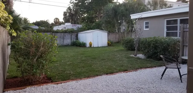 a backyard of a house with table and chairs plants and large trees