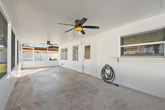 a view of a livingroom with wooden floor a ceiling fan and windows