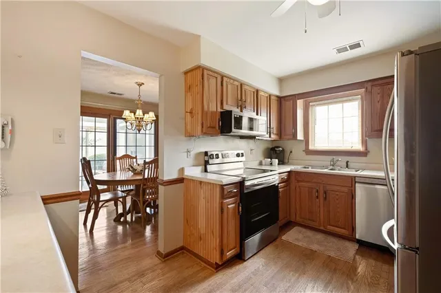 a kitchen with stainless steel appliances granite countertop a stove top oven a sink dishwasher a dining table and chairs with wooden floor