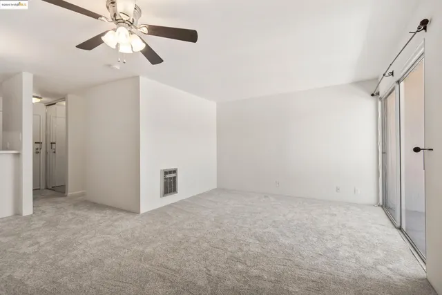 an empty room with closet and a ceiling fan