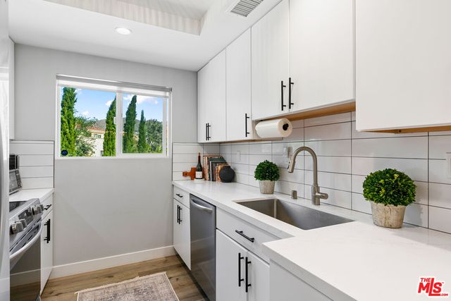 a kitchen with stainless steel appliances a sink a window and cabinets