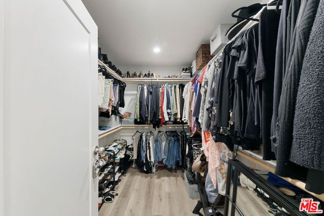 a view of walk in closet with clothes and shoes