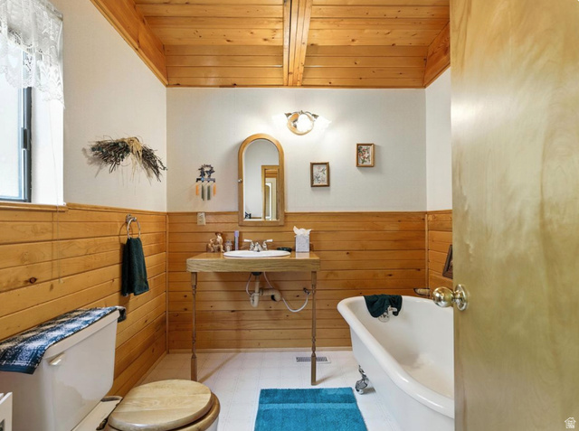 1180 Oak Road Coalville, UT 84017 - Photo 17 of 28 Wood-paneled walls and ceiling beams, freestanding vanity with integrated sink, and a clawfoot tub