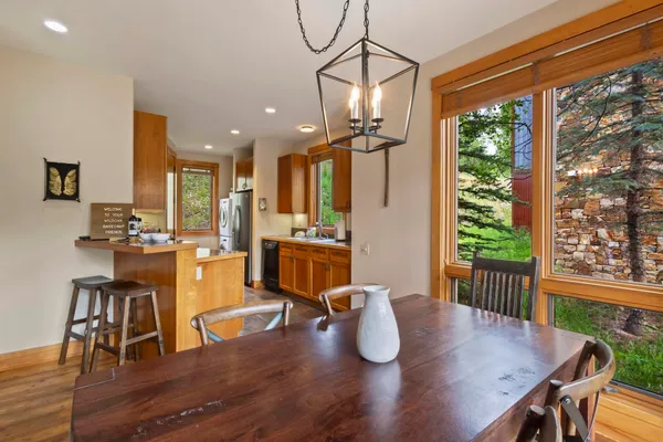 a dining room with wooden floor a chandelier a wooden table and chairs
