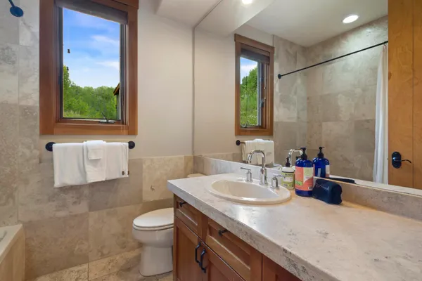 a bathroom with a granite countertop sink a toilet a mirror and shower