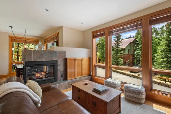 a living room with furniture a fireplace and floor to ceiling window