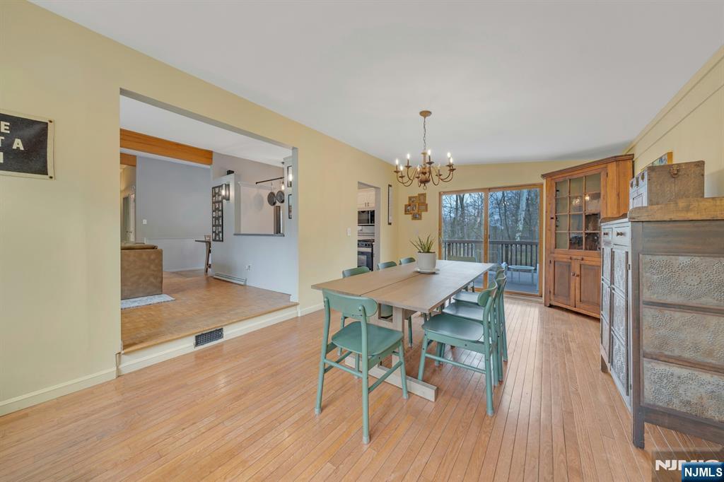 27 Bear Mountain Road Ringwood, NJ 07456 - Photo 19 of 47 a dining room with wooden floor a chandelier a wooden table and chairs