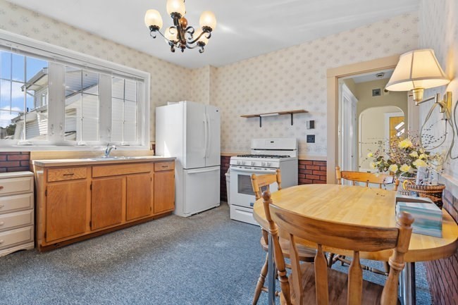 53 Windsor Street Everett, MA 02149 - Photo 3 of 20 a kitchen with a table chairs refrigerator and cabinets