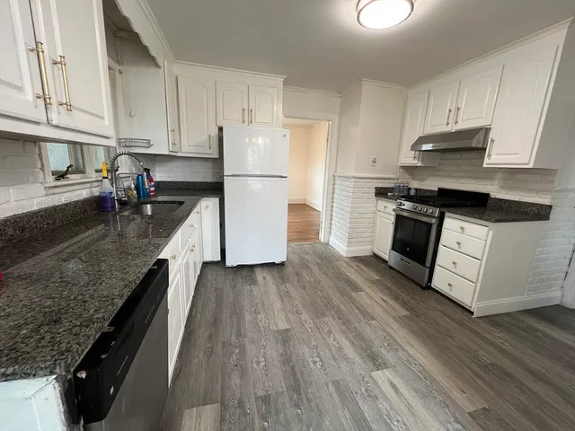 a kitchen with granite countertop a sink a counter space stainless steel appliances and cabinets