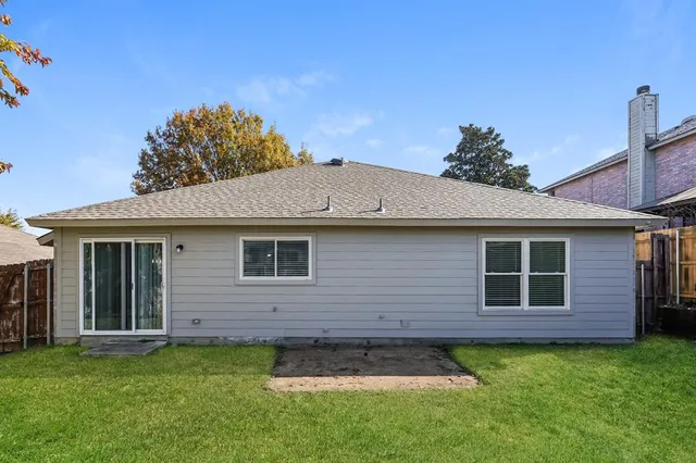 a backyard of a house with plants and wooden fence