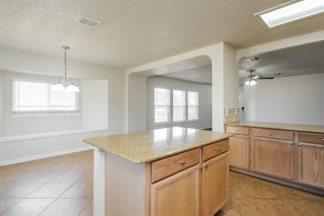 a kitchen with granite countertop a sink dishwasher and white cabinets with wooden floor