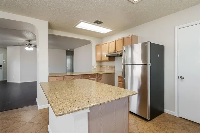 a kitchen with refrigerator and wooden floor
