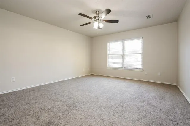 an empty room with windows and ceiling fan