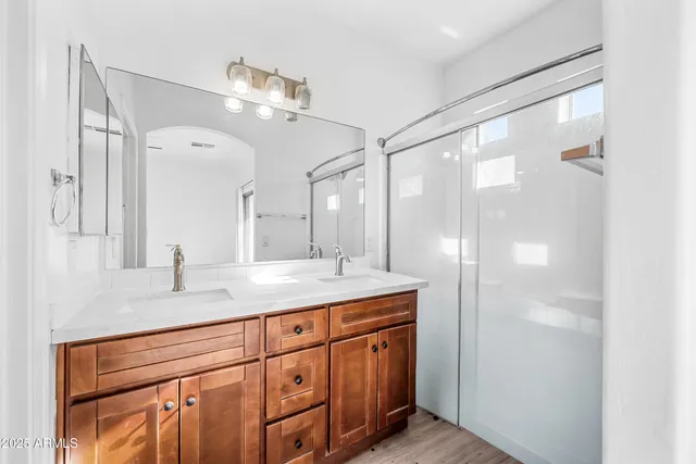 a bathroom with a granite countertop sink a mirror and a shower