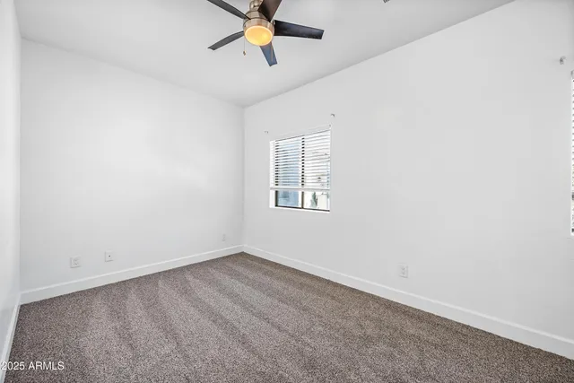an empty room with a window and a fan