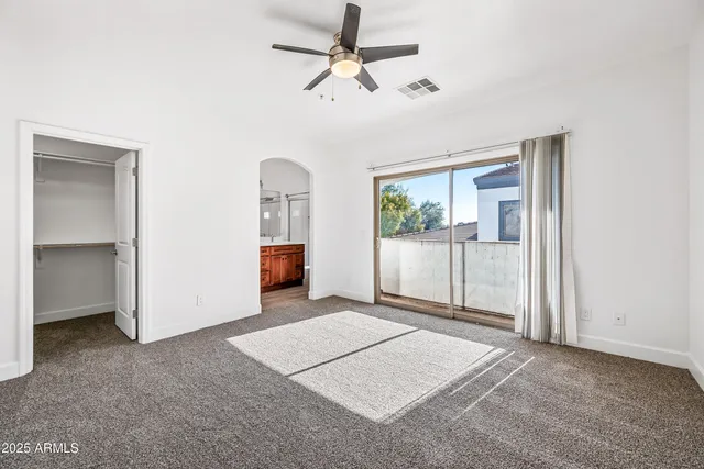 an empty room with windows and ceiling fan