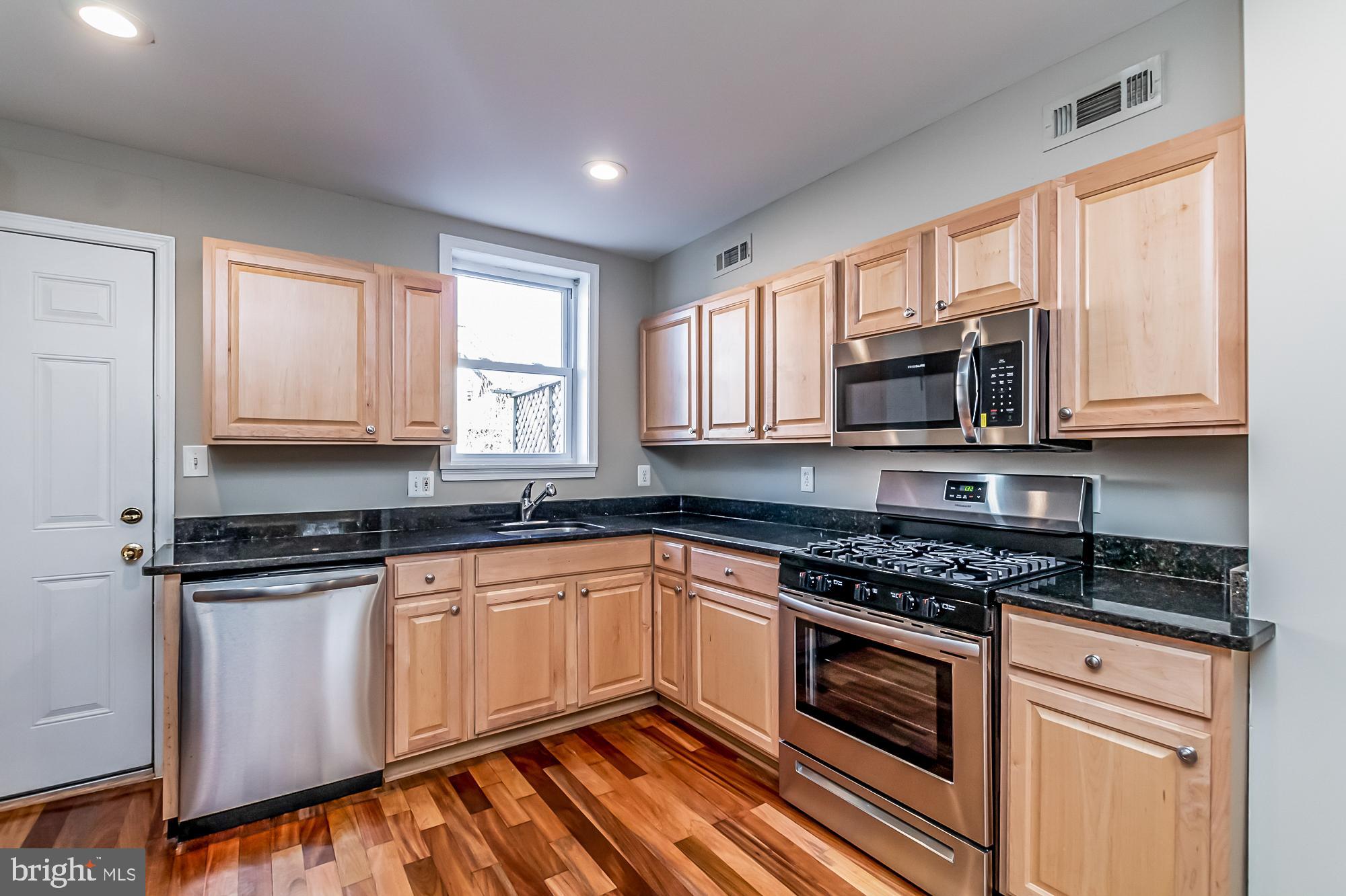 130 West Randall Street Baltimore, MD 21230 - Photo 10 of 30 a kitchen with granite countertop a stove top oven microwave and cabinets