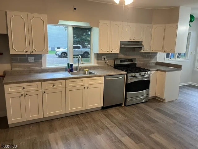 a kitchen with stainless steel appliances granite countertop a sink a stove a refrigerator and cabinets