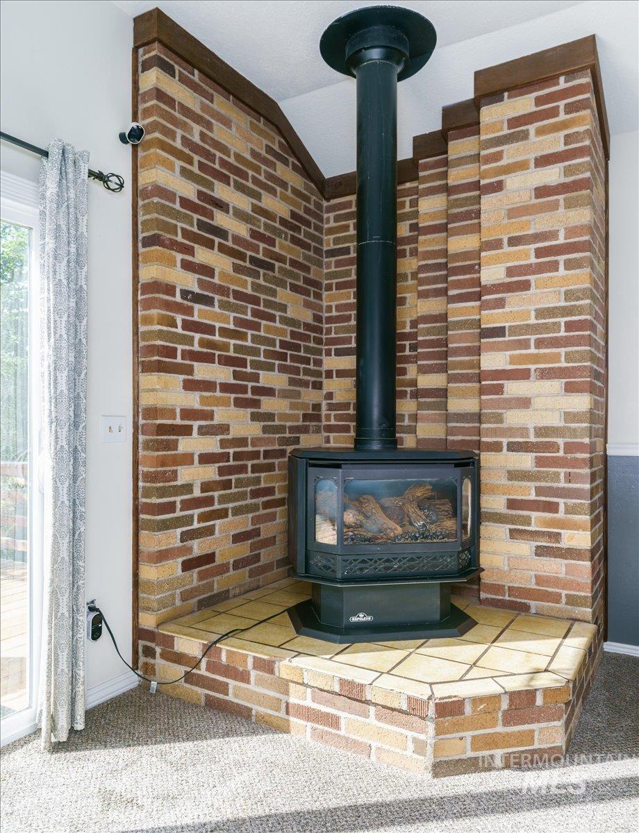 1401 Chokecherry Drive Pocatello, ID 83204 - Photo 12 of 46 Corner-positioned brick fireplace with a black stove insert and tiled hearth, complemented by wood trim accents