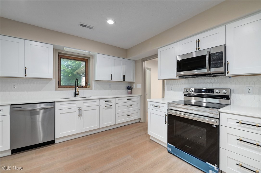 433 Chestnut Road Independence, OH 44131 - Photo 18 of 50 Kitchen featuring appliances with stainless steel finishes, light countertops, light wood-style floors, white cabinets, and recessed lighting